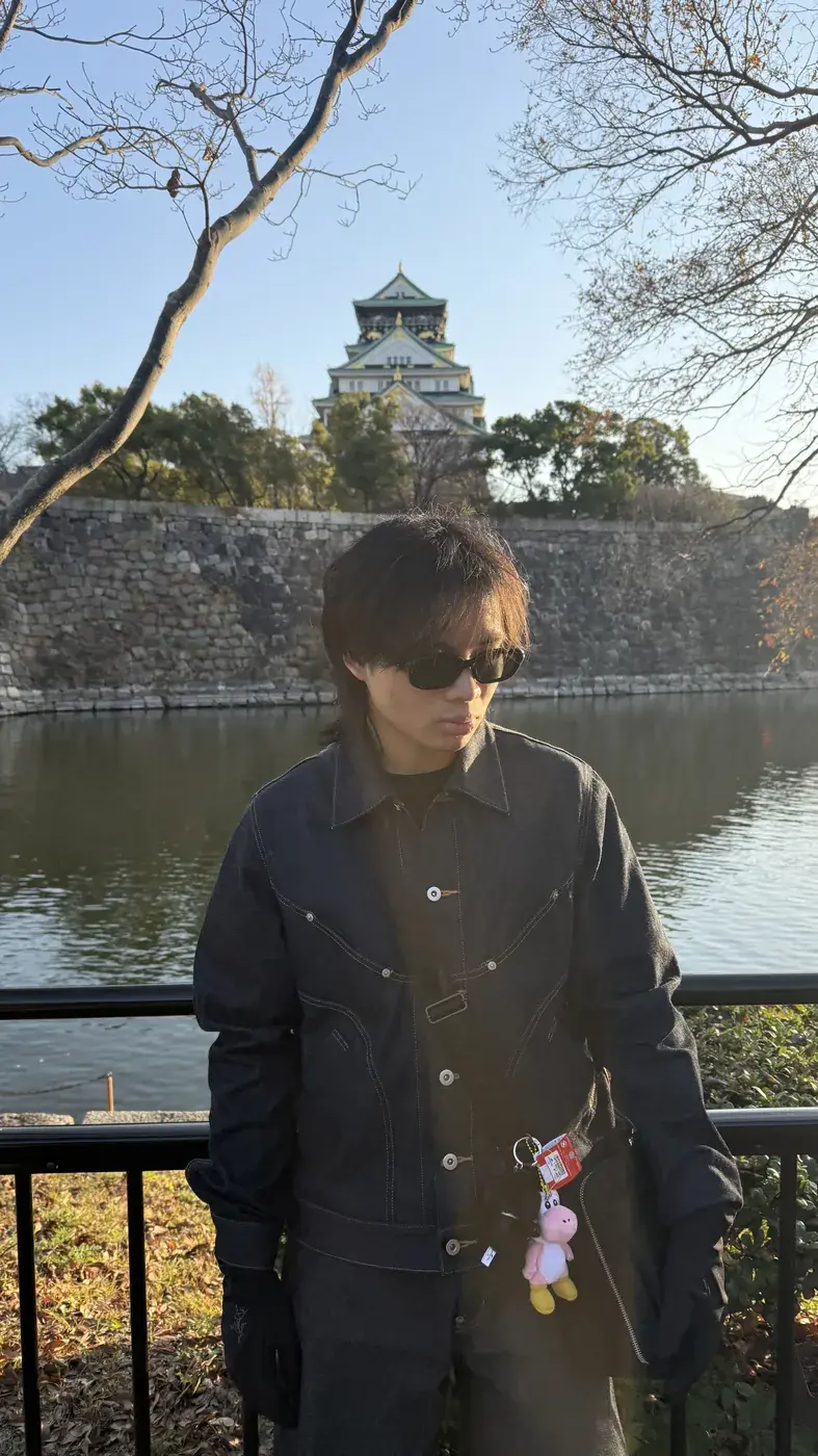 Elliot by a moat below a castle on a clear day