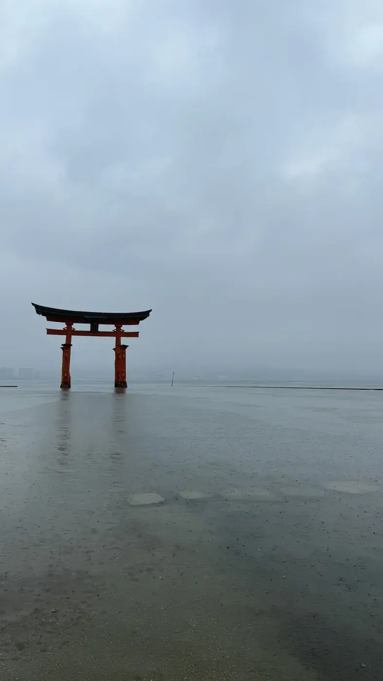 A red torii gate standing in calm grey water