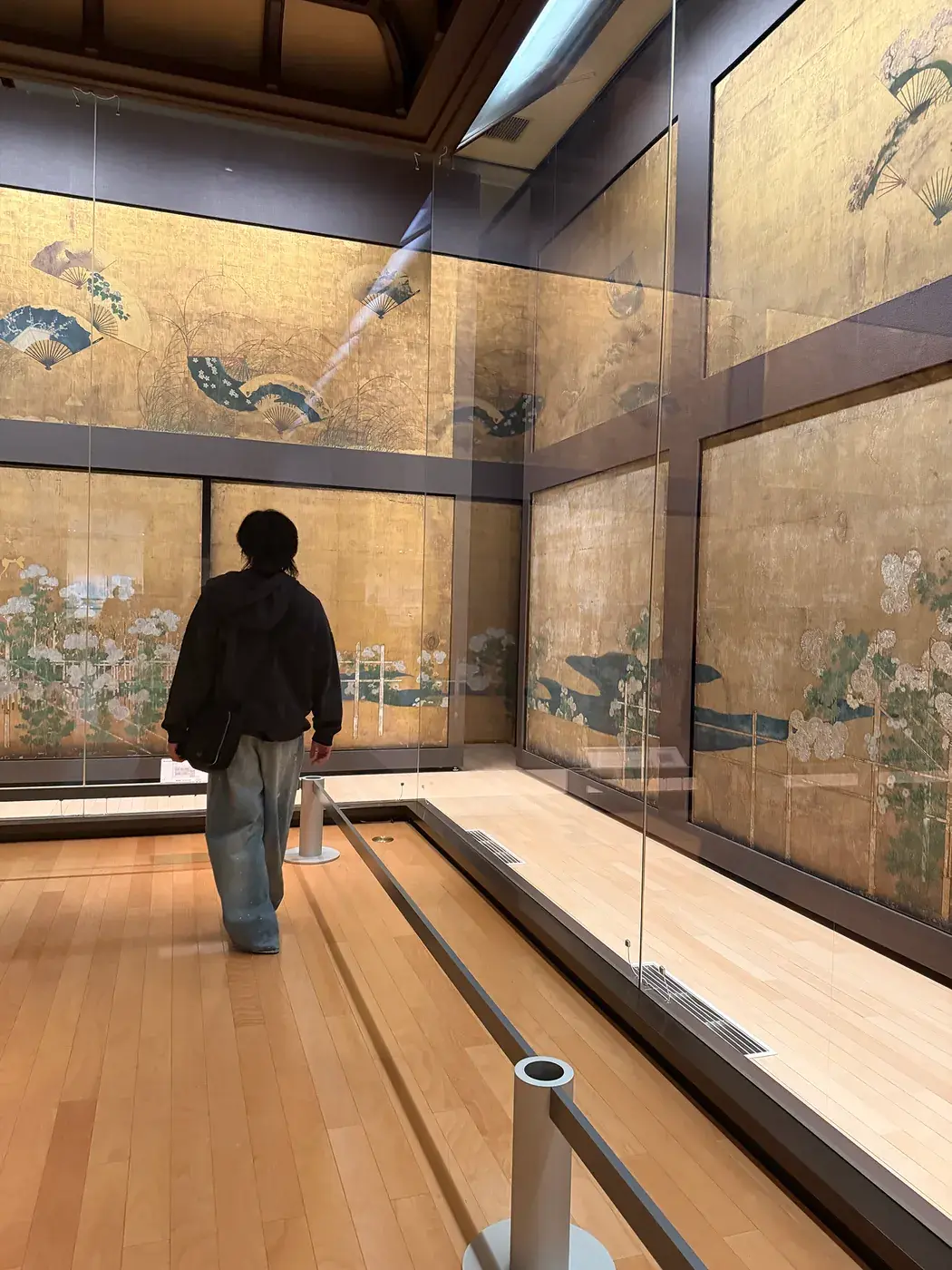 Elliot walking through a gallery of gold folding screens