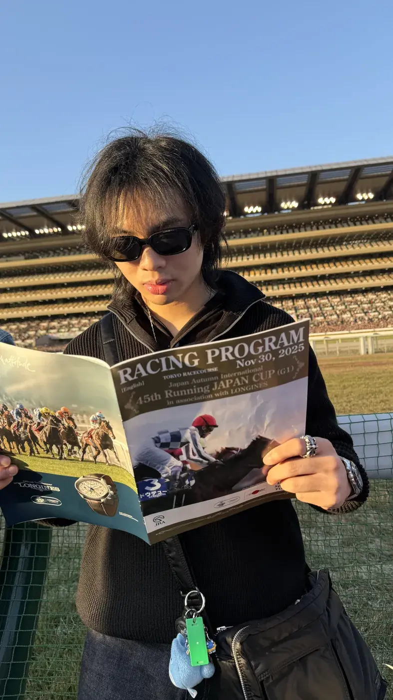 Elliot in sunglasses reading a horse racing program