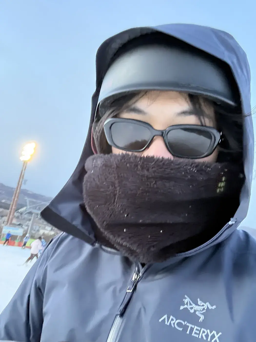 Elliot in a ski jacket, sunglasses and face mask on the slopes