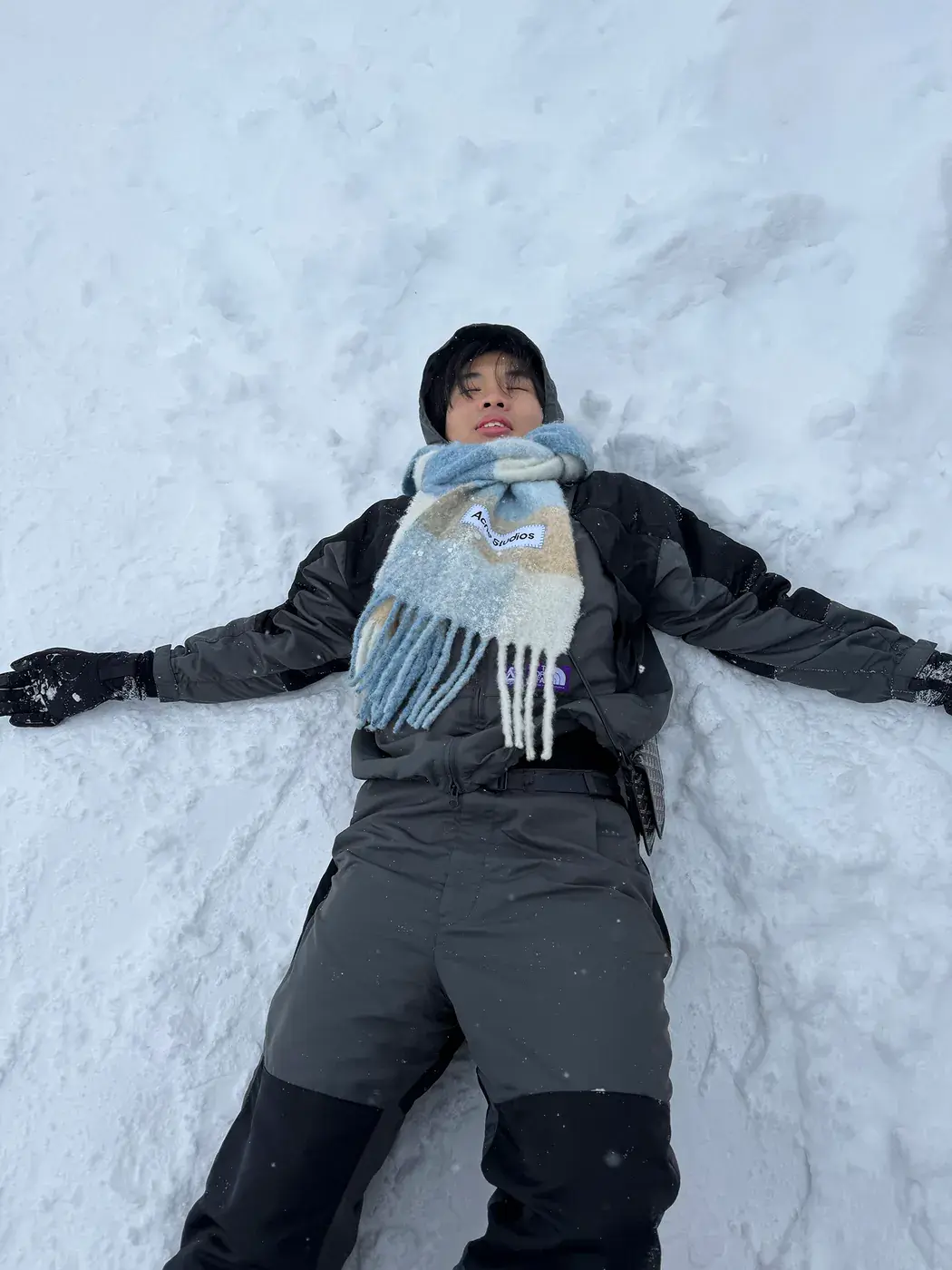 Elliot lying in deep snow making a snow angel