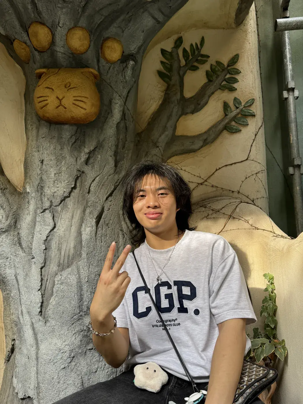 Elliot smiling, sitting in a sculpted tree with a cat face