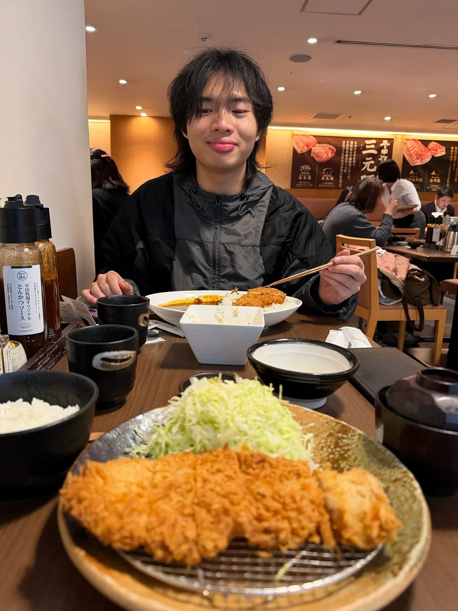 Elliot smiling over a meal of tonkatsu and rice